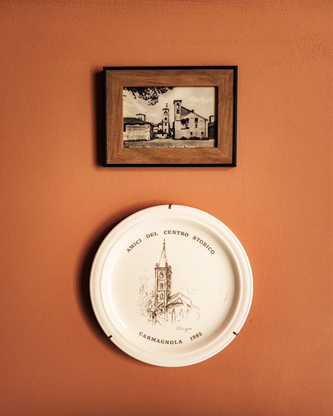 Una vecchia fotografia di Carmagnola e un piatto decorativo appesi alla parete