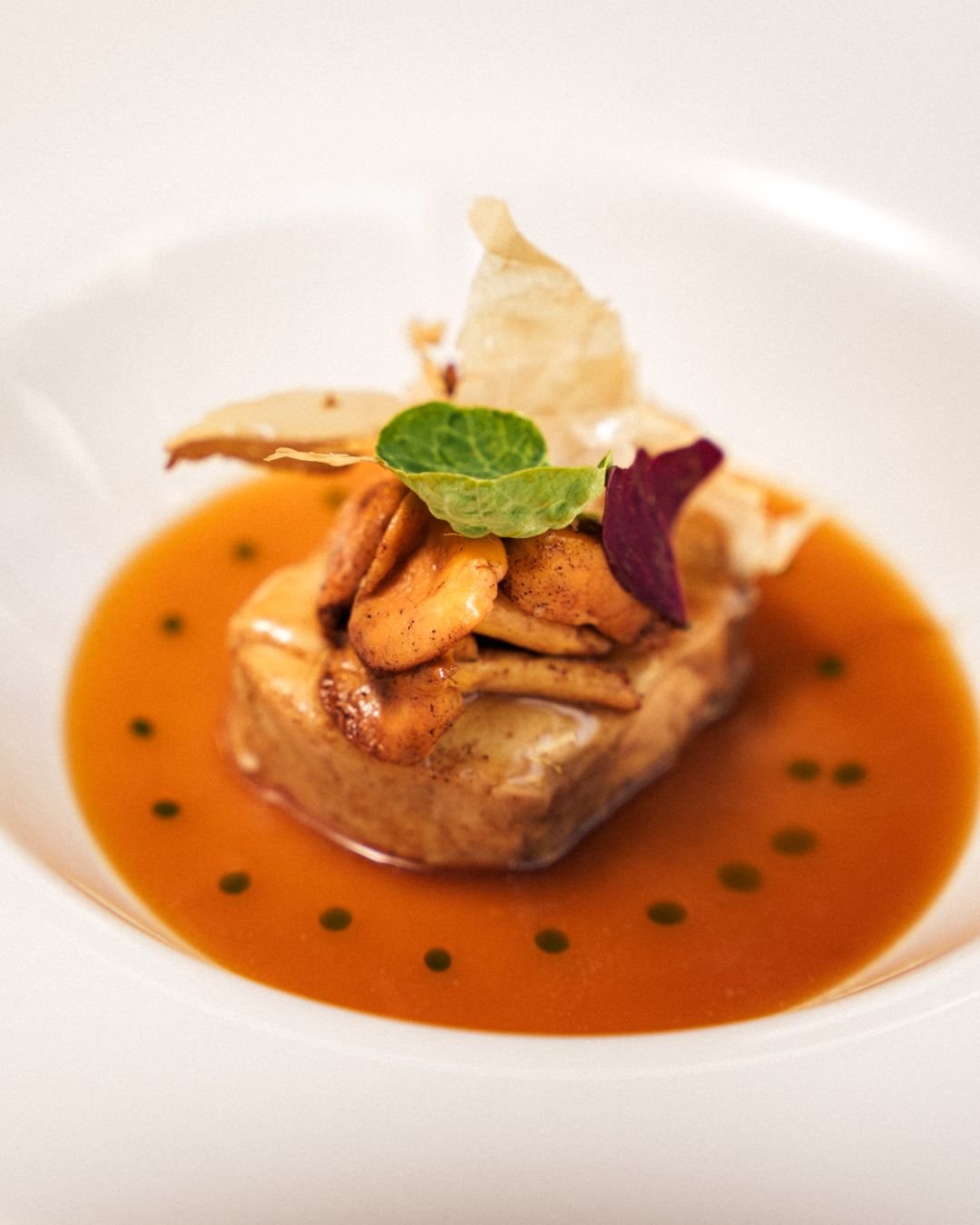 Piatto di Casa Lanzafame: Piatto con salsa arancione, foglie e fiori